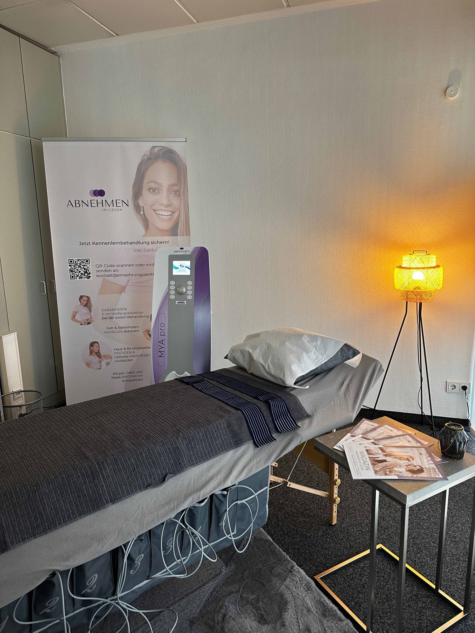 Behandlungsliege mit Decke, Rollup-Banner und MVA.pro-Gerät im Behandlungsraum