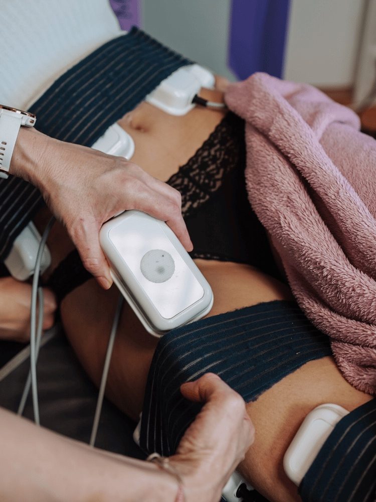 Nahaufnahme: Hände legen eine Elektrode am Bauch einer Kundin an